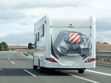 Rückansicht eines Wohnmobils, das über eine leere Straße fährt.