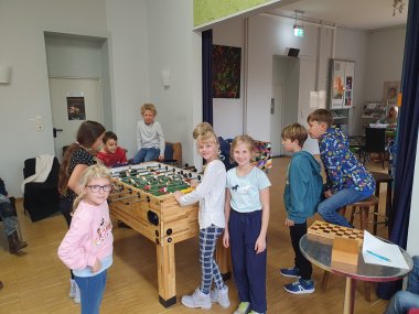 Herbstfreizeit im Jukz Lahnstein Eine Gruppe von Kindern spielt gemeinsam an einem Tischkicker in einem hellen Innenraum.