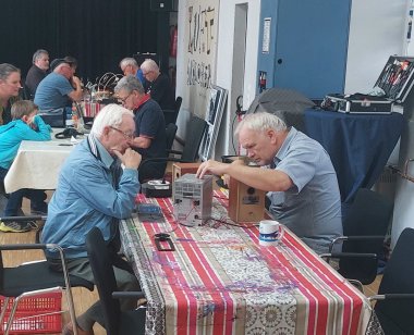 Männer reparieren im Repair Café alte Elektrogeräte