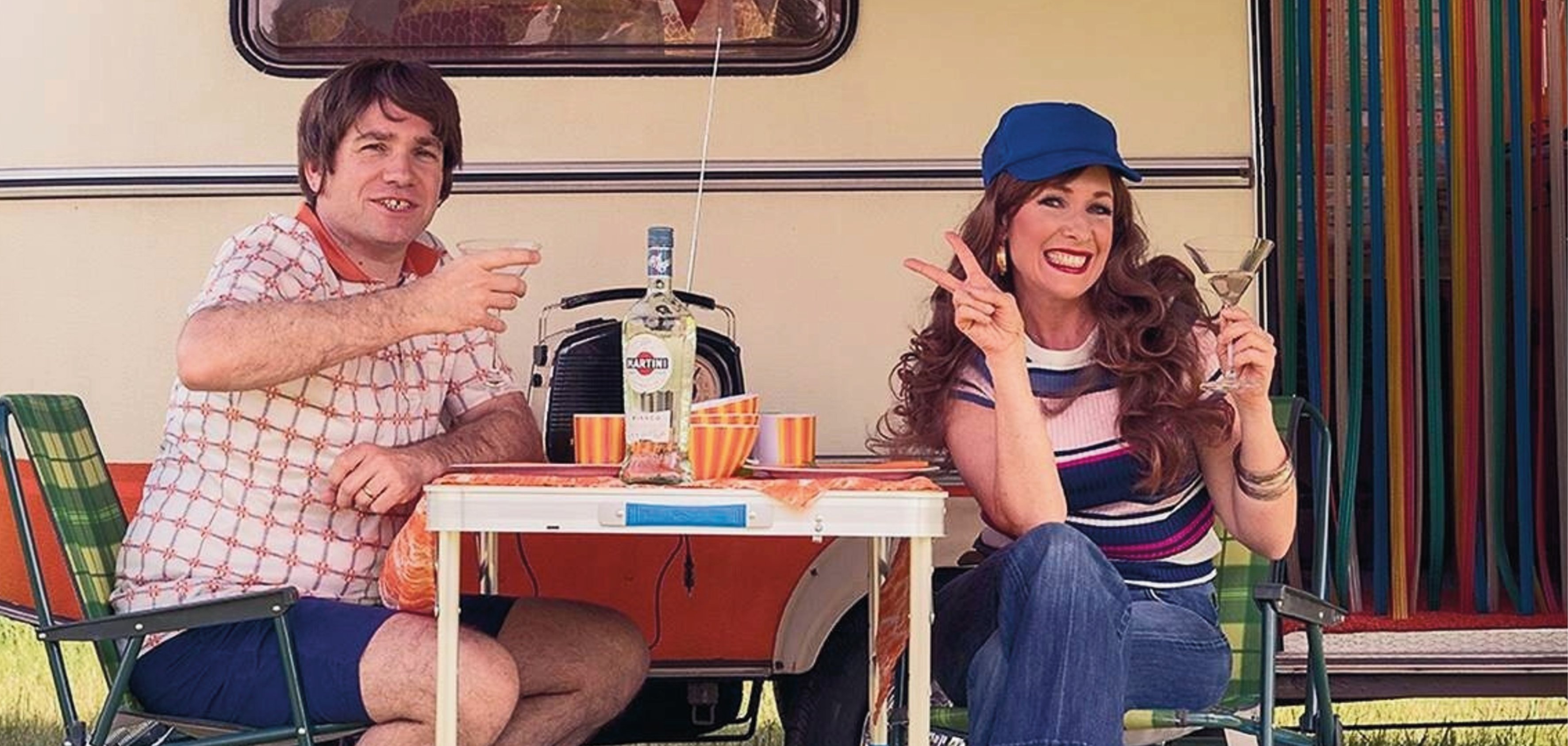 Veranstaltungsplakat zum Theaterstück „Campingplatz Sardella – Das Recht zu campen“ im Theater Lahnstein. Vor einem Wohnwagen sitzen zwei Frauen an einem Campingtisch mit Getränken und weiteren Gegenständen. Das Plakat kündigt die Aufführungen vom 12. bis 21. September 2025 im Sporkenburger Hof an.