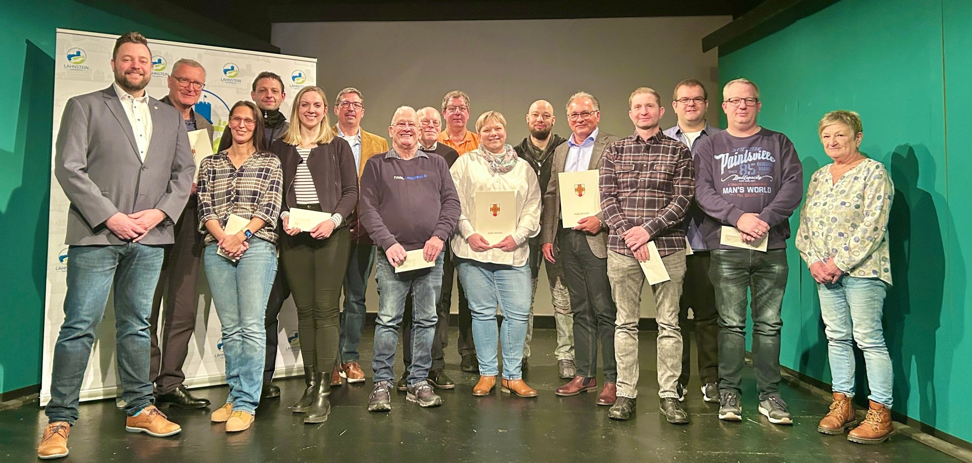 Eine Gruppe von Personen, darunter die Geehrten sowie der Oberbürgermeister und die Sachgebietsleiter, stehen auf der Bühne im Theater Lahnstein.