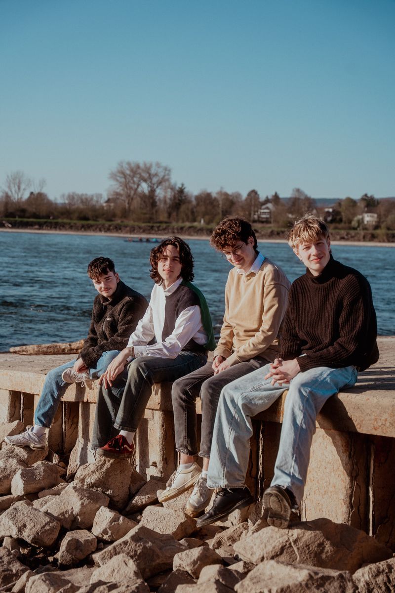 Die aus vier Musikern bestehende Band Herbstwind sitzt auf einer Mauer.