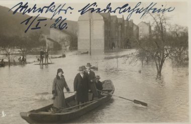 Hochwasser in der Markstraße, 1926 Foto eines Hochwassers in Lahnstein aus dem Jahr 1926. Im Vordergrund sind Menschen auf einem kleinen Boot, hinten sind weitere Menschen sowie überschwemmte Straßen und Häuser erkennbar.
