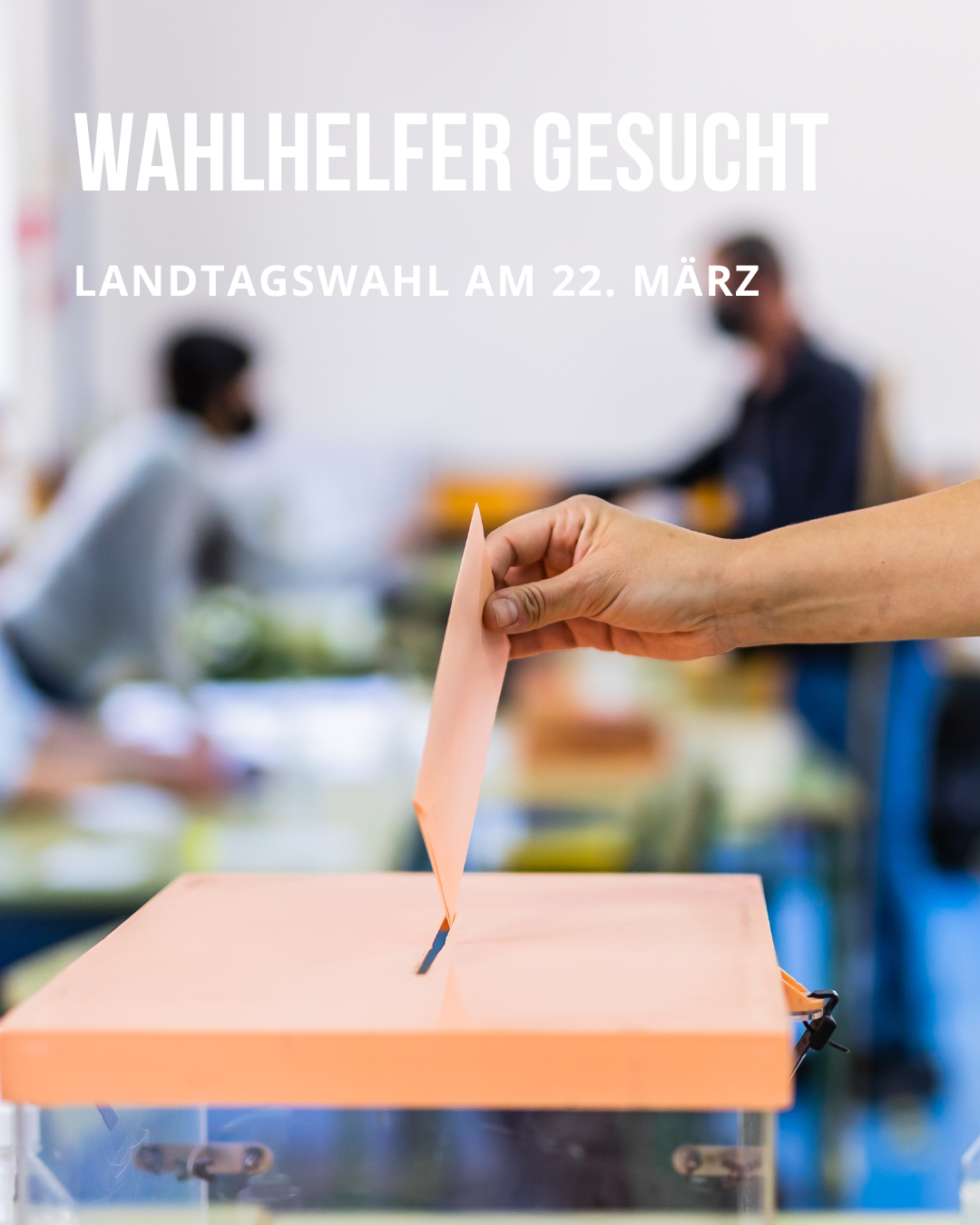 Im Hintergrund sind verschwommen zwei Personen zu erkennen, während im Vordergrund eine durchsichtige Wahlurne steht, in die gerade ein Brief eingeworfen wird. 