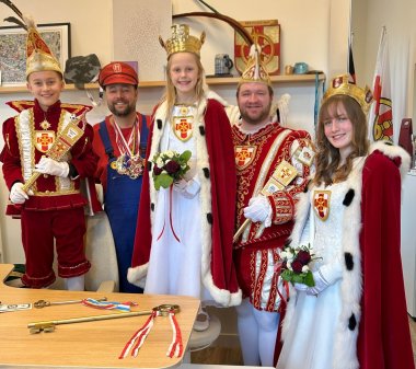 Die Narren haben OB Lennart Siefert vom Chefsessel verjagt. Das Prinzenpaar sowie das Kinderprinzenpaar in Tracht stehen zusammen mit dem als Super Mario verkleideten Oberbürgermeister Lennart Siefert hinter dessen Schreibtisch.