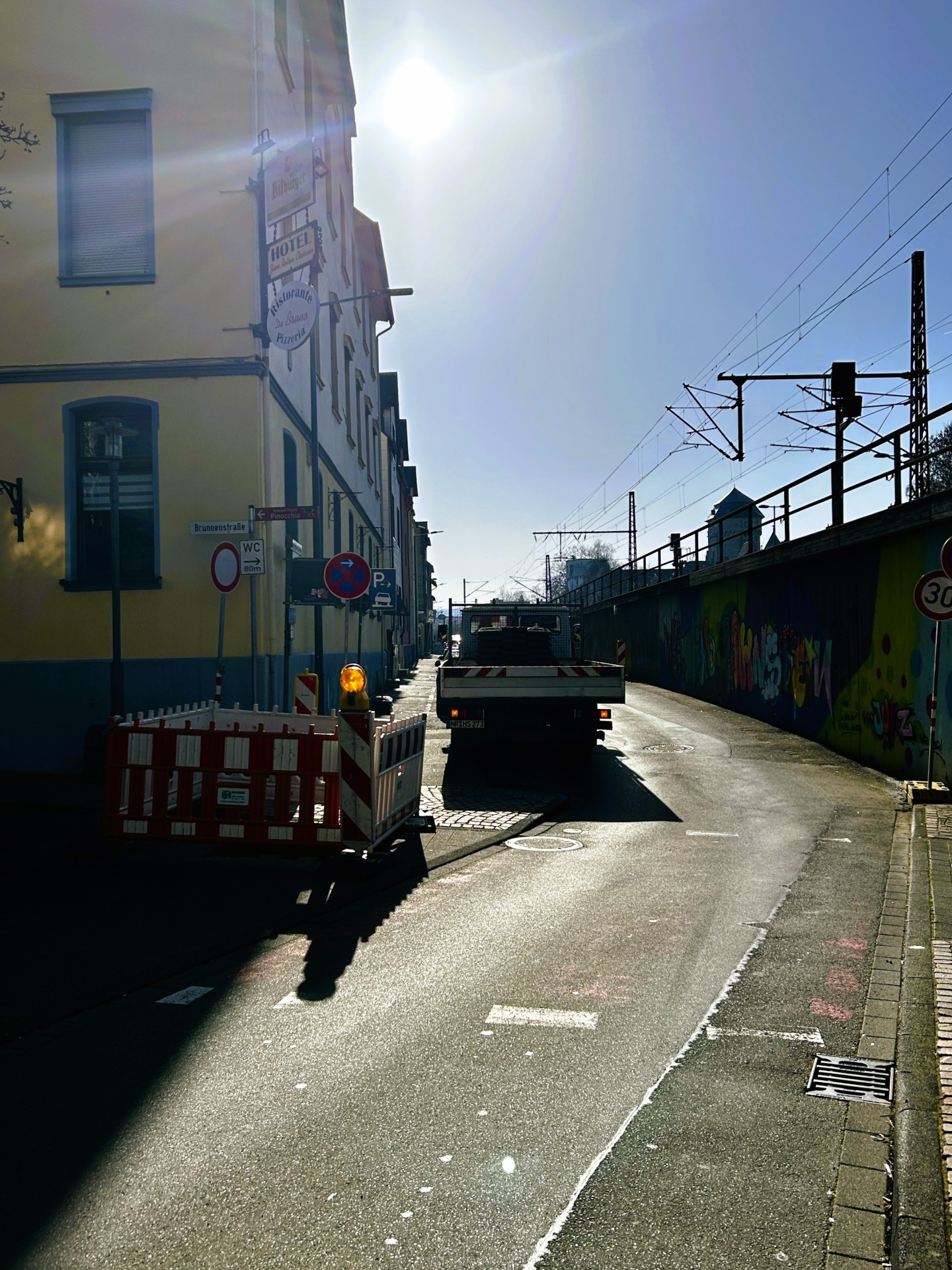 Eine Straße mit Seitenstraße, Absperrbarke und einem Baufahrfahrzeug