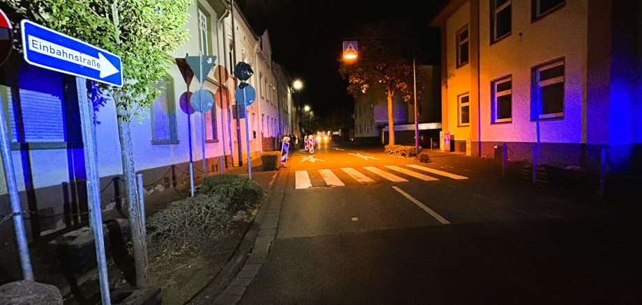 Eine Straße im Wohngebiet mit beidseitiger Häuserbebauung und teilweise Begrünung. Im Vordergrund links ist ein Schild mit der Aufschrift Einbahnstraße.