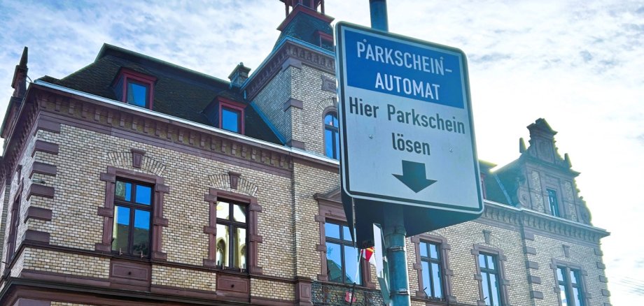 Vor dem städtischen Rathaus ist ein Parkscheinautomat an der Straße mit Hinweisschild zu sehen.