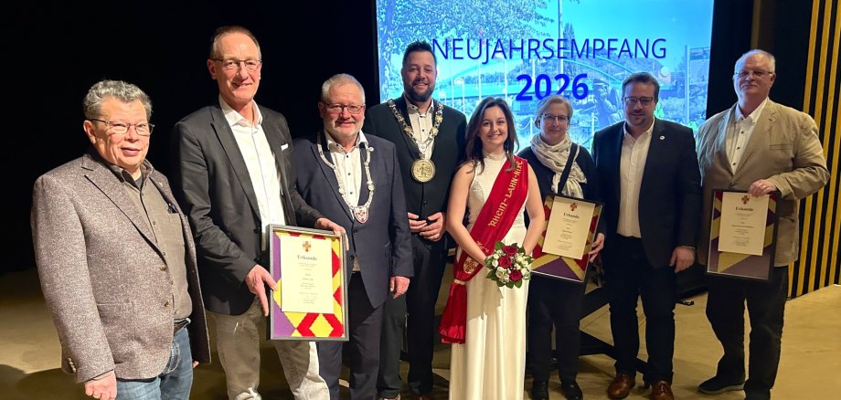 Geehrte beim Neujahrsempfang der Stadt Lahnstein 2026 Die drei beim Neujahrsempfang der Stadt Lahnstein 2026 geehrten Personen stehen zusammen mit dem Oberbürgermeister, dem Bürgermeister, den Beigeordneten und der Rhein-Lahn-Nixe auf der Bühne der Stadthalle Lahnstein.