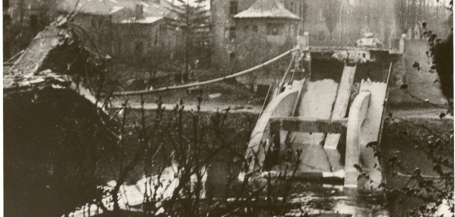 Schwarz-Weiß-Foto eines Panzers vor zerstörter Lahnbrücke