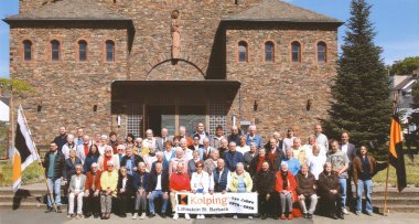 Vom Gesellenverein zur Kolpingfamilie Ein historisches, sepiafarbenes Gruppenfoto einer Theatergruppe. Die Personen tragen aufwendige historische Kostüme mit Hüten, Kragen und Waffen wie Schwertern, während sie auf einer Bühne mit gemaltem Hintergrund posieren.