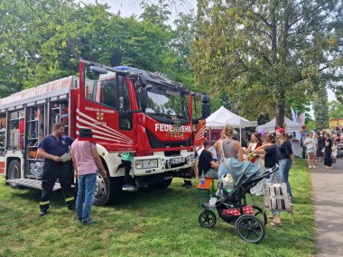Ein Feuerwehrfahrzeug der Freiwilligen Feuerwehr Lahnstein ist Teil des Kinderprogramms der Openair-Veranstaltung Lahneck Live. Kinder erkunden das Fahrzeug, während Familien und Besucherinnen und Besucher über das Veranstaltungsgelände zwischen verschiedenen Aktionsständen schlendern.