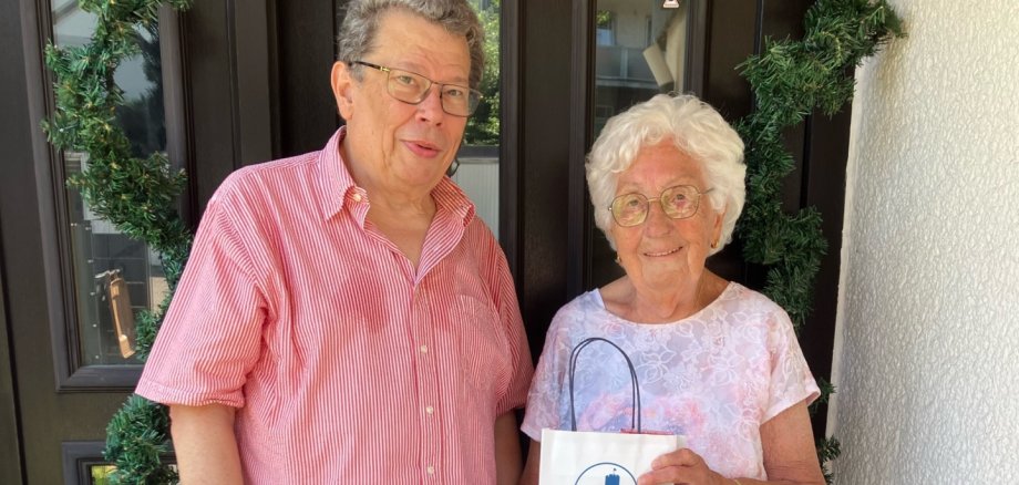 Ein Mann und eine Frau stehen zusammen vor einer braunen Tür: Der Beigeordnete Manfred Radermacher gratuliert Elisabeth Heiser zu ihrem 90. Geburtstag. Beide lächeln in die Kamera.