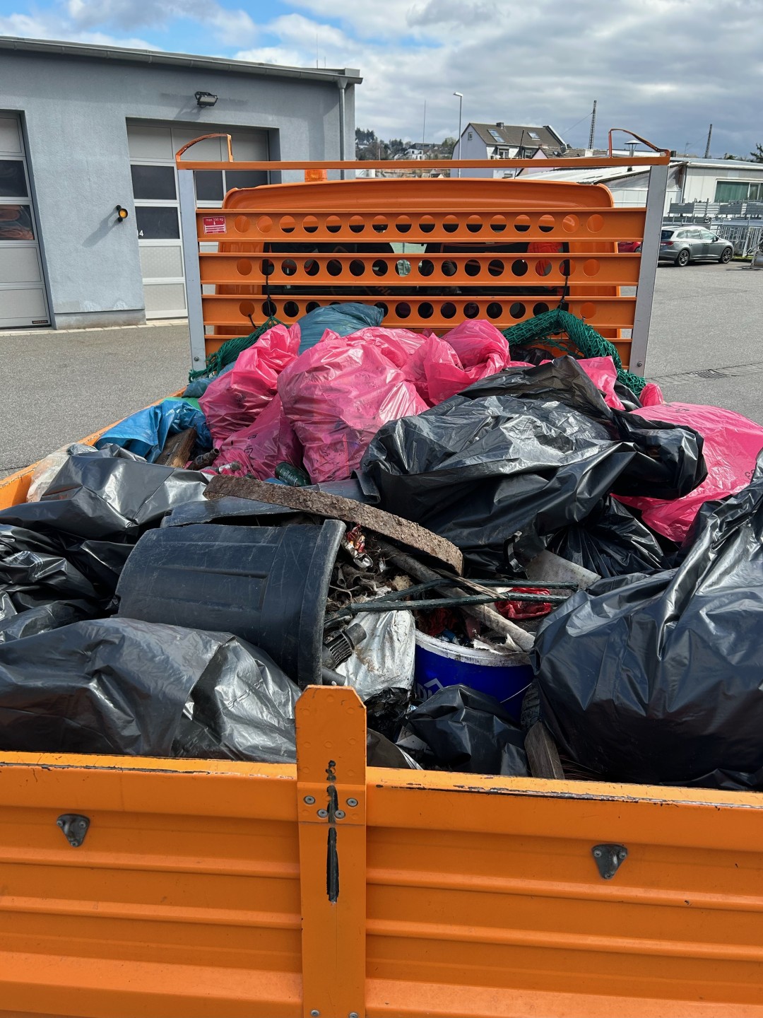 Auf der Ladefläche eines orangefarbenen LKW des Bauhofs stapeln sich die beim Lahnsteiner Frühjahrsputz gesammelten Müllsäcke verschiedener Farben.