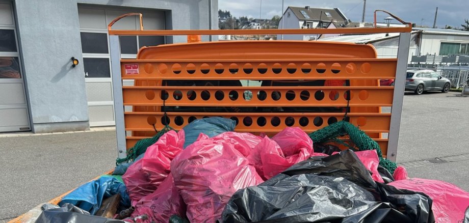 Lahnsteiner Frühjahrsputz Auf der Ladefläche eines orangefarbenen LKW des Bauhofs stapeln sich die beim Lahnsteiner Frühjahrsputz gesammelten Müllsäcke verschiedener Farben.