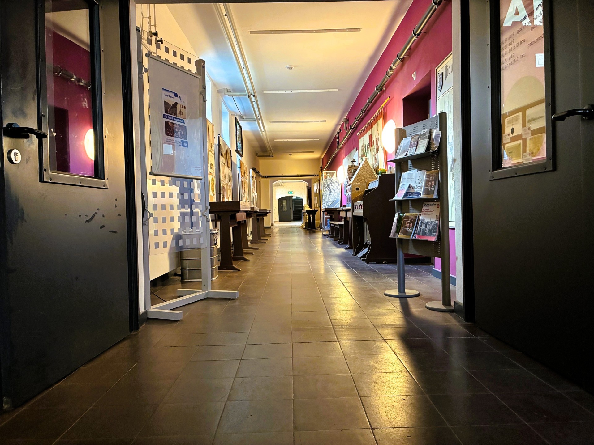 Der Flur des Stadtarchivs mit Ausstellungstafeln an den Seiten sowie Bildmaterial an der rot gestrichenen rechten Wand