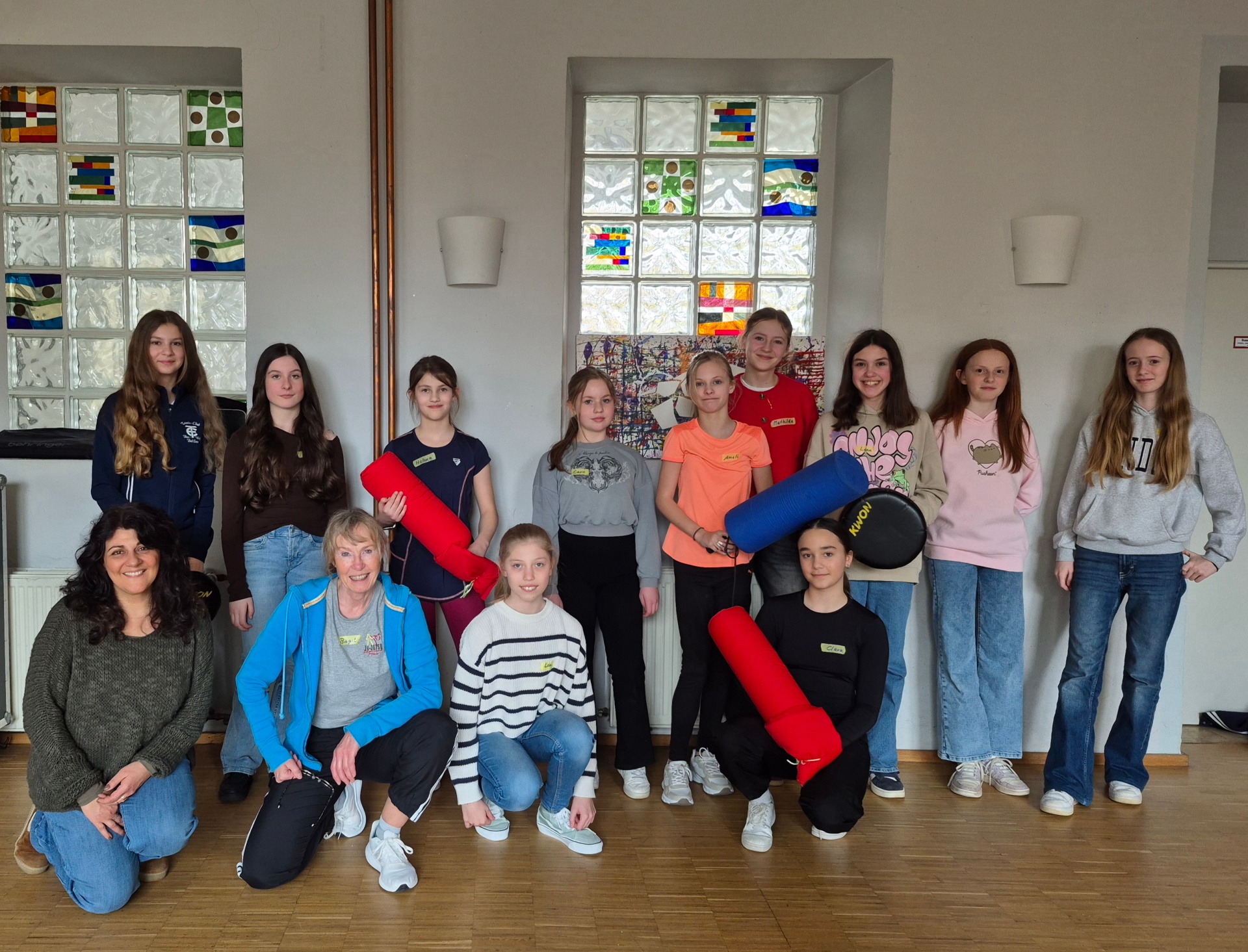 9 Mädchen stehen in zweiter Reihe und zwei Mädchen und zwei Frauen hocken in erster Reihe davor und posieren für ein Foto.