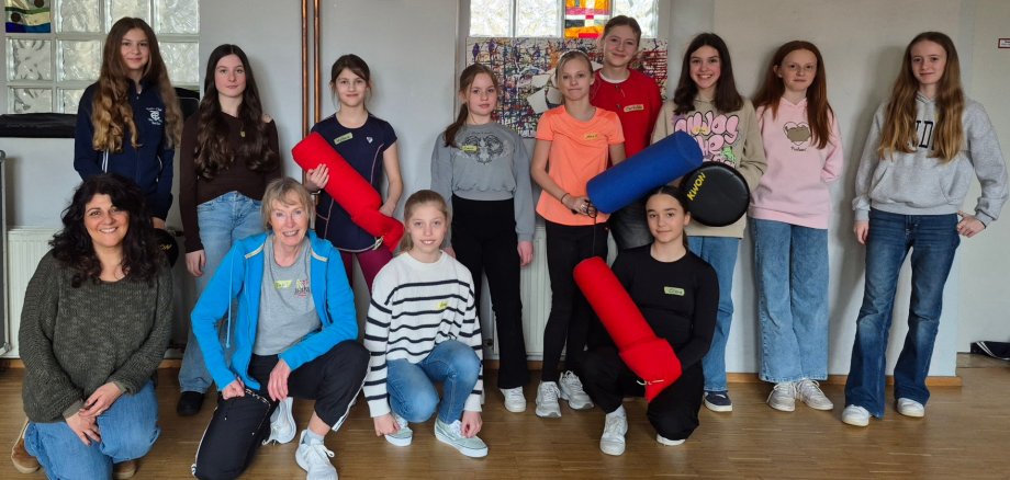 9 Mädchen stehen in zweiter Reihe und zwei Mädchen und zwei Frauen hocken in erster Reihe davor und posieren für ein Foto.