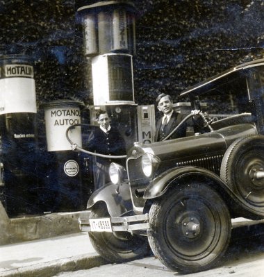 Vor 125 Jahren wurde Lorenz Schlösser geboren Schwarzweißfoto: Zwei Männer tanken einen offenen Oldtimer an einer historischen Zapfsäule mit der Aufschrift „Motanol“.