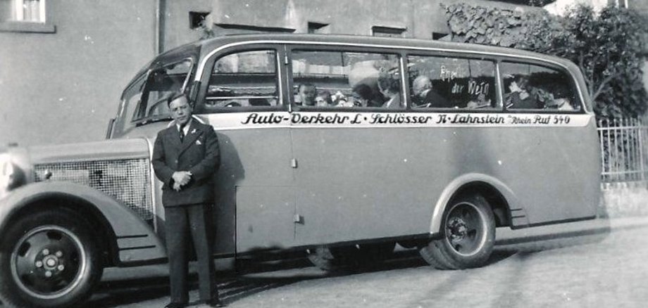 Vor 125 Jahren wurde Lorenz Schlösser geboren Schwarzweißfoto: Ein Mann im Anzug steht vor einem historischen Linienbus mit der Aufschrift eines Verkehrsunternehmens.