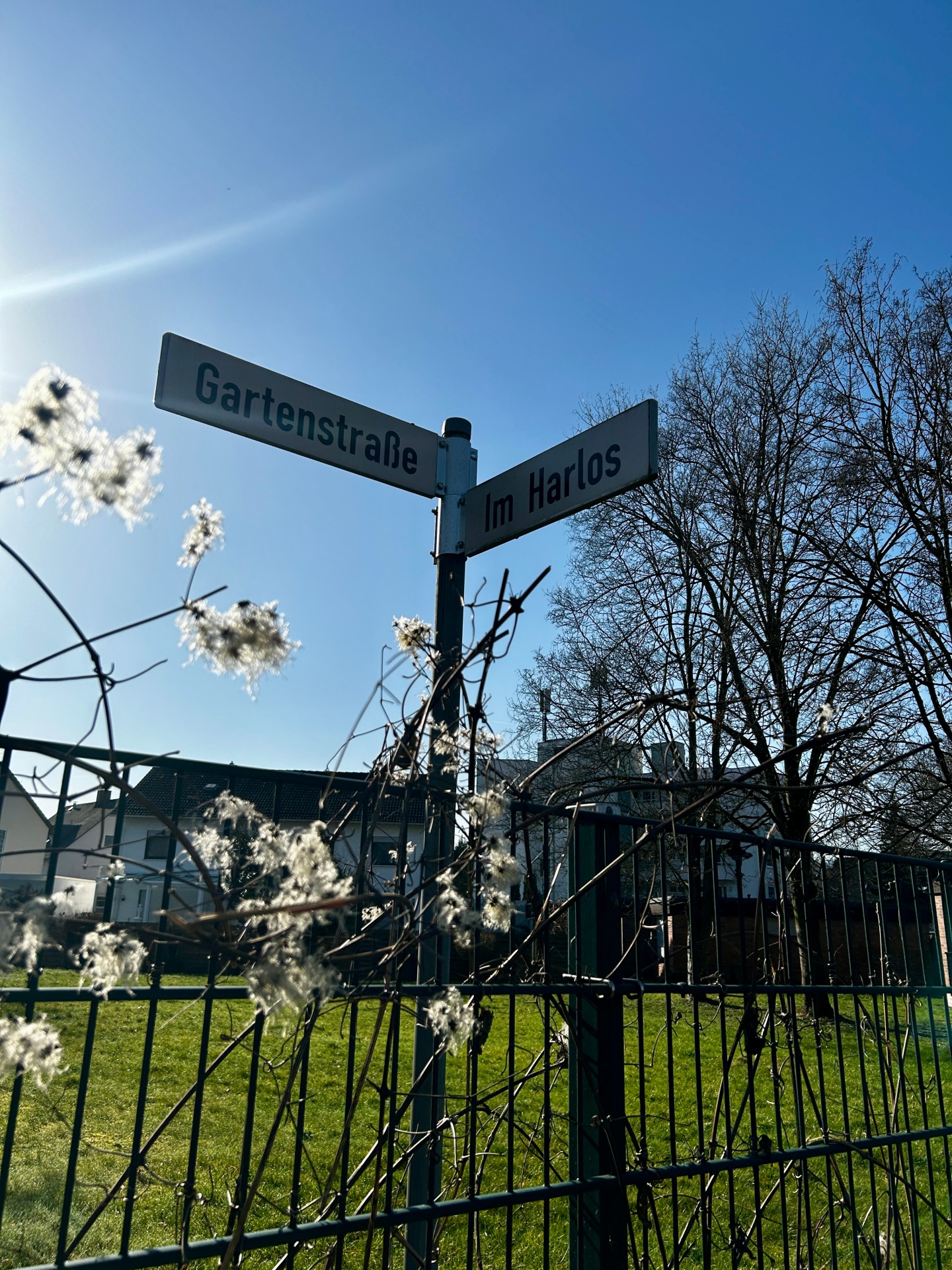 Zwei sich kreuzende Straßenschilder mit dem Name "Im Harlos" und "Gartenstraße"