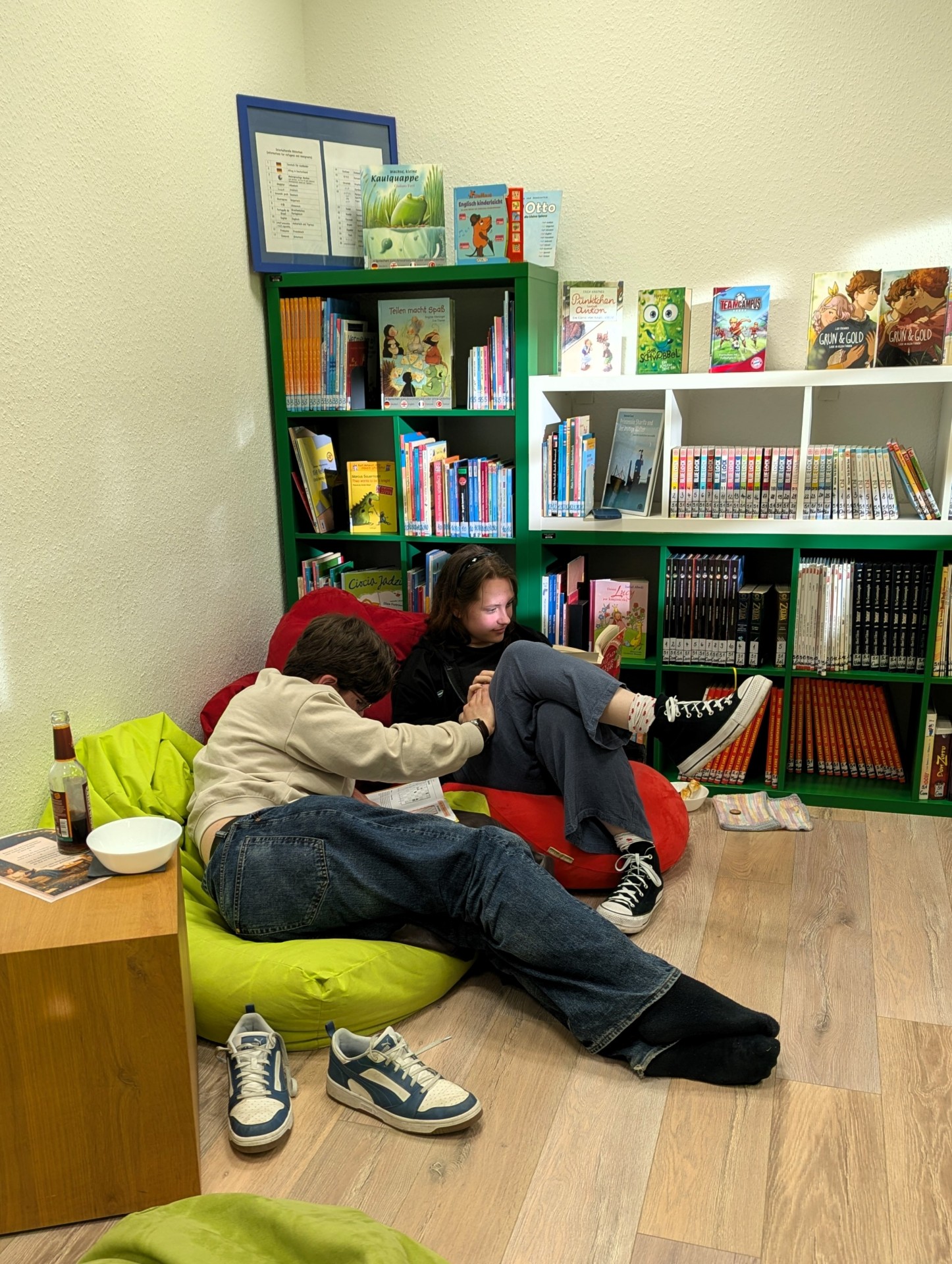 Zwei Jugendliche sitzen gemütlich auf bunten Sitzsäcken in der Stadtbücherei Lahnstein und lesen konzentriert in ihren Büchern. Im Hintergrund stehen gut gefüllte Bücherregale mit Kinder- und Jugendbüchern, die eine ruhige und entspannte Atmosphäre schaffen.
