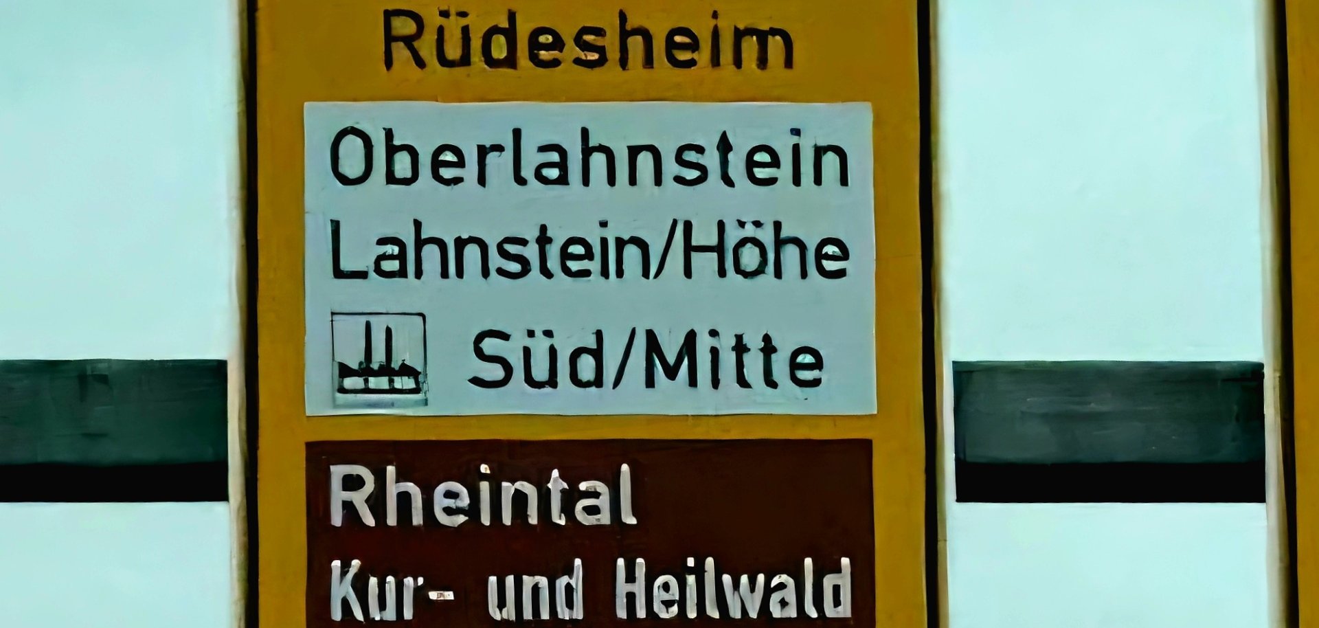 Ein gelbes Straßenverkehrsschild, auf dem neben der Richtungsanzeige Oberlahnstein auf braunem Untergrund auf die POI Rheintal sowie Kur- und Heilwald Lahnstein hinwiesen wird