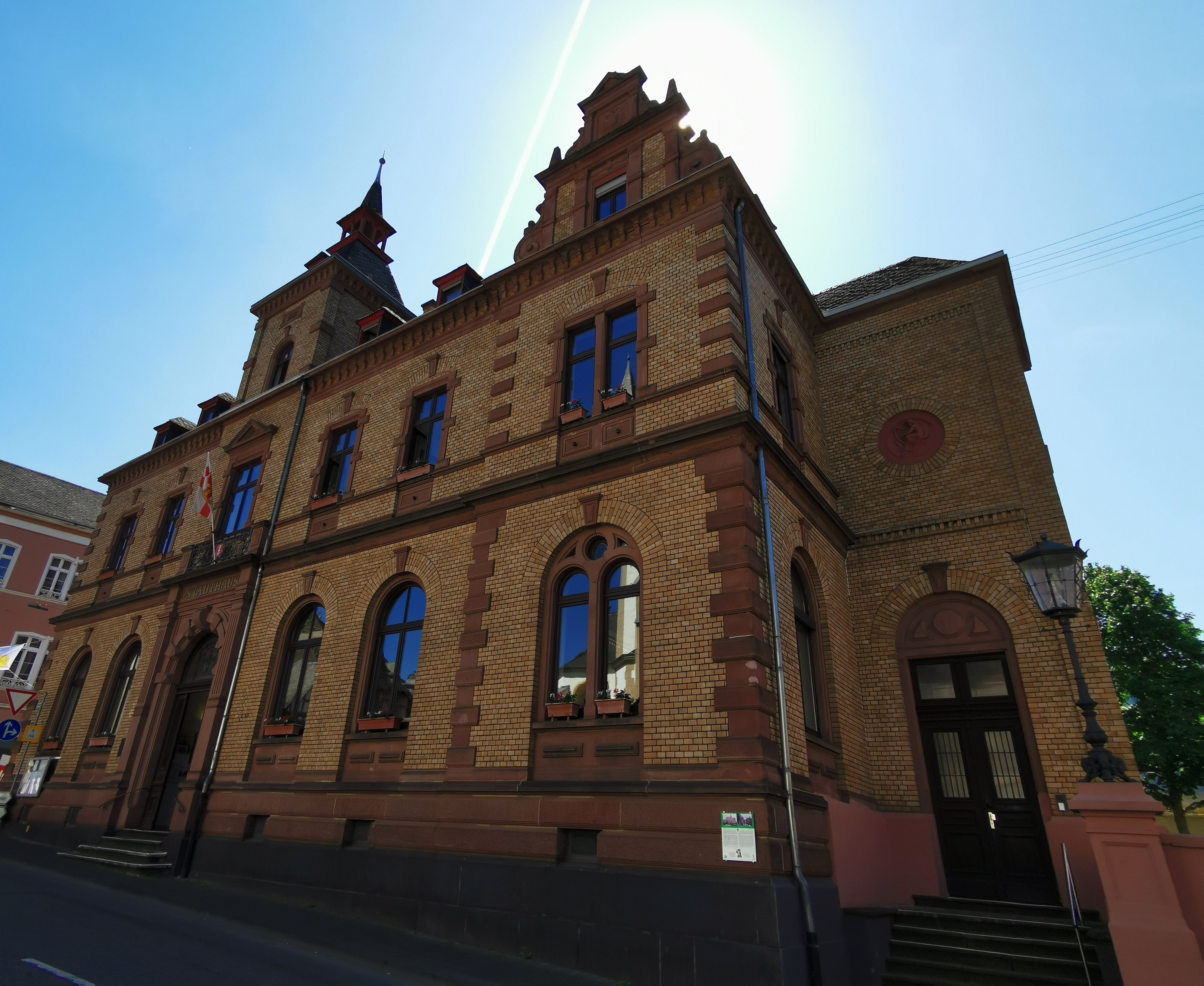 Das Rathaus Oberlahnstein ist aus der Untersicht fotografiert. Die reich verzierte Sandsteinfassade mit den hohen Fenstern und dem markanten Giebel hebt sich gegen den blauen Himmel ab.
