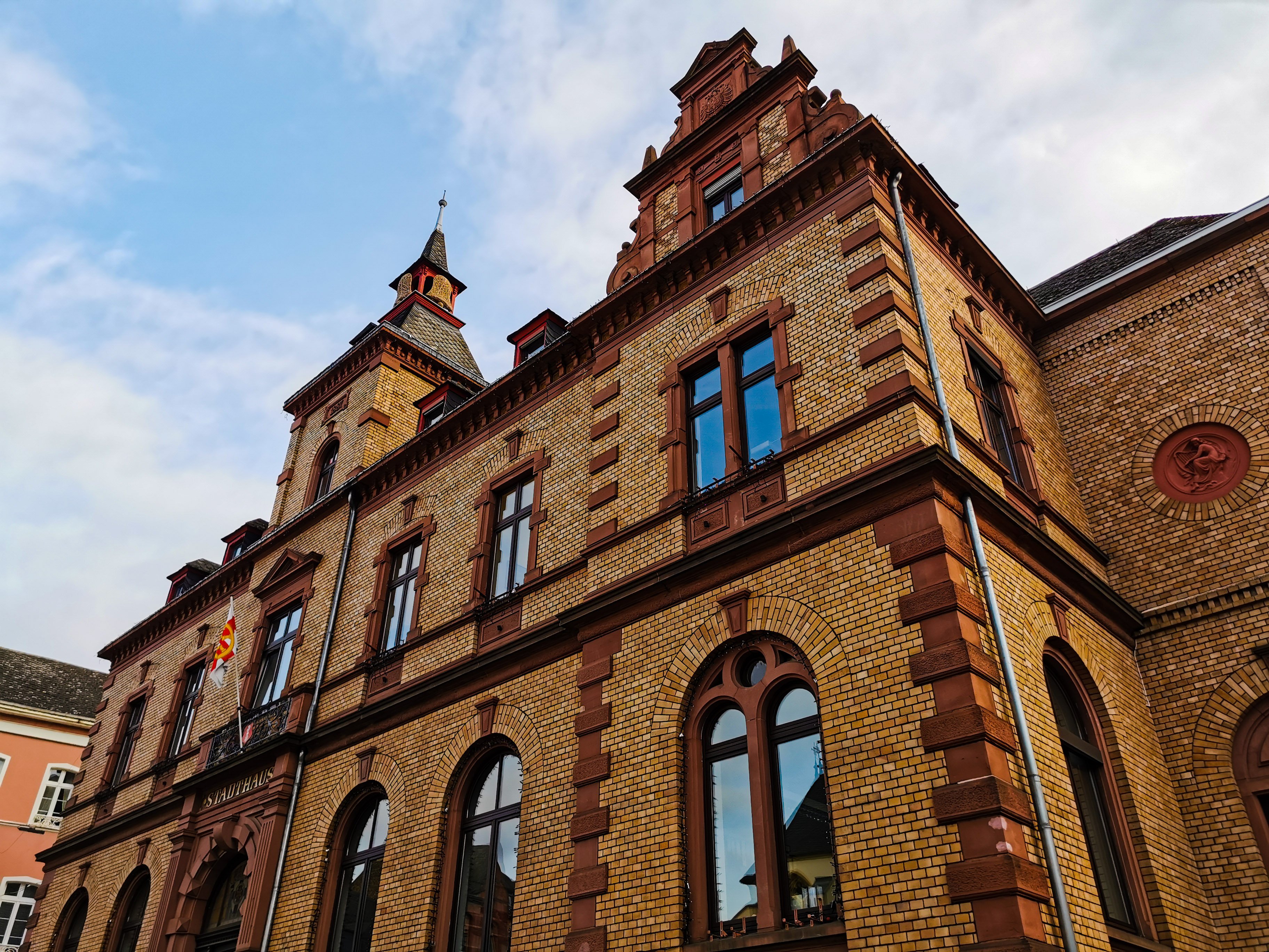 Schräger Blick auf das Rathaus Oberlahnstein mit seiner aufwendig gestalteten Sandsteinfassade und den charakteristischen Giebeln unter blauem Himmel mit leichten Wolken. Die Aufnahme betont die Architektur des denkmalgeschützten Gebäudes.