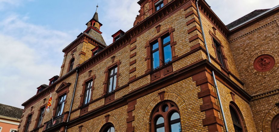 Schräger Blick auf das Rathaus Oberlahnstein mit seiner aufwendig gestalteten Sandsteinfassade und den charakteristischen Giebeln unter blauem Himmel mit leichten Wolken. Die Aufnahme betont die Architektur des denkmalgeschützten Gebäudes.