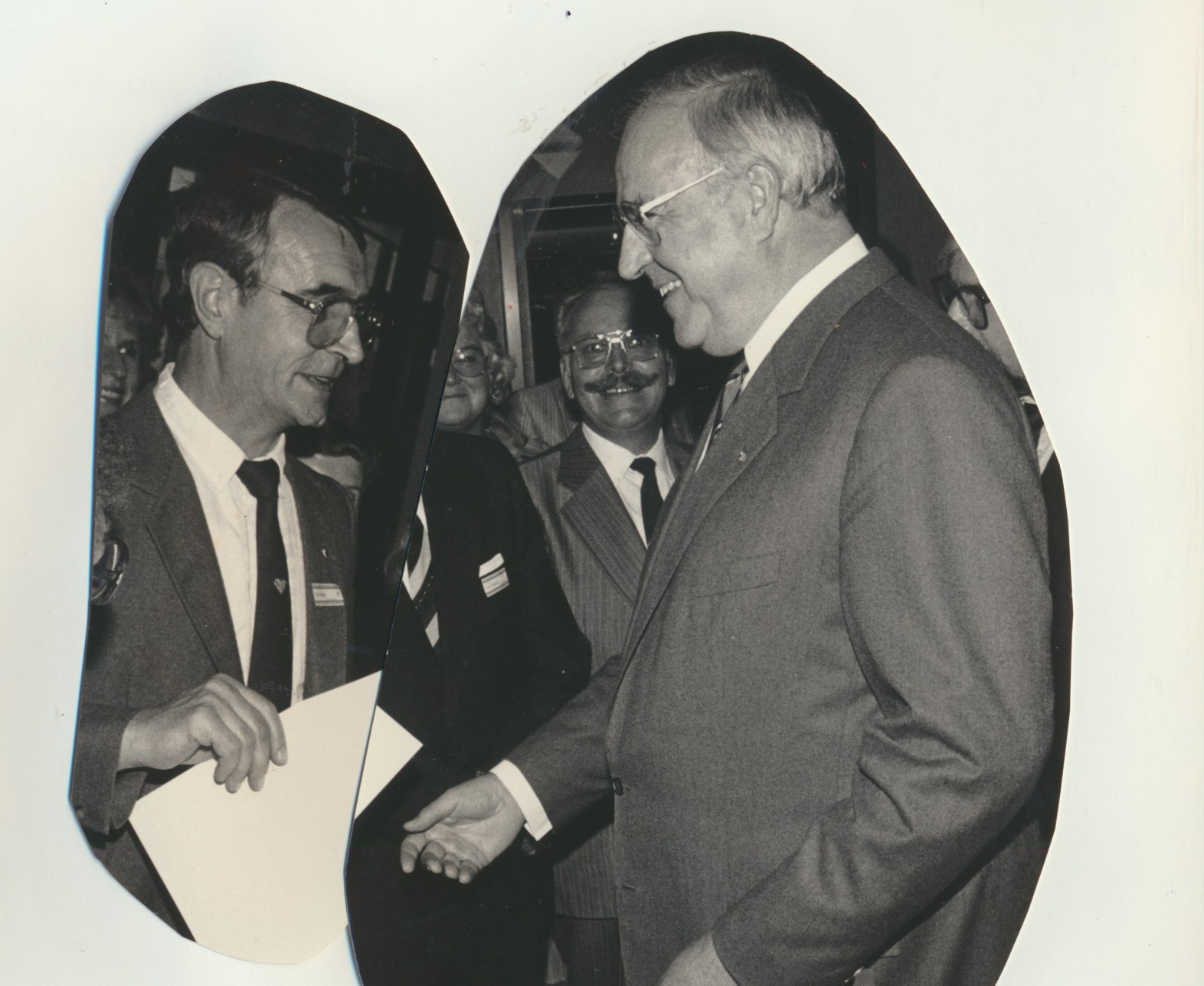 Schwarz-Weiß-Foto: Zwei Männer in Anzügen, rechts steht der damalige Bundeskanzler Helmut Kohl, links der gewürdigte Hans Hoffmann aus Lahnstein, stehen einander bei einer Veranstaltung gegenüber und unterhalten sich. Im Hintergrund sind weitere lächelnde Personen zu sehen.