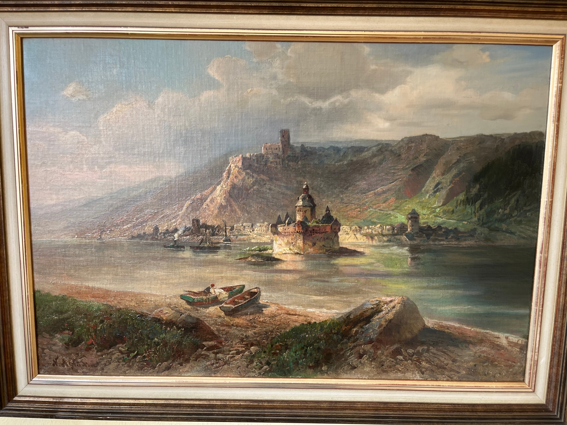 Gemälde einer Rheinlandschaft mit Burg auf einem steilen Felsen, ruhigem Fluss im Vordergrund und kleinen Booten am Ufer; warme Lichtstimmung und detailreiche Naturdarstellung.