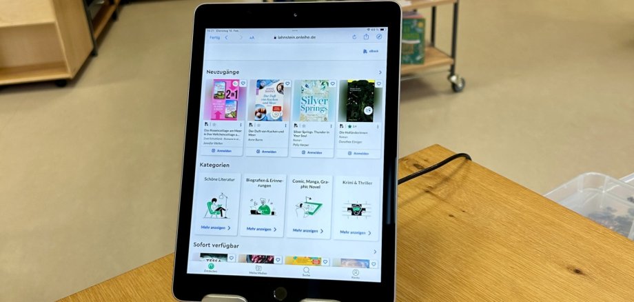 Bei der eBook-Sprechstunde erhalten Interessierte praktische Hilfe rund um die digitale Ausleihe von Medien über die Onleihe. Ein Tablet zeigt die Startseite der Onleihe mit verschiedenen eBook-Angeboten. Vor dem Gerät liegen Informationsbroschüren zur digitalen Ausleihe. Im Hintergrund sind die Regale und Buchbestände der Stadtbücherei Lahnstein erkennbar.