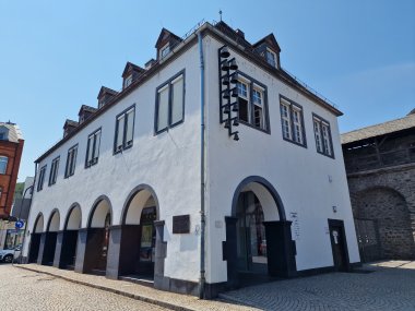 Salhof Lahnstein Weißes historisches Gebäude mit dunklen Fensterläden und Rundbögen im Erdgeschoss. Vor dem Gebäude befindet sich ein gepflasterter Platz.