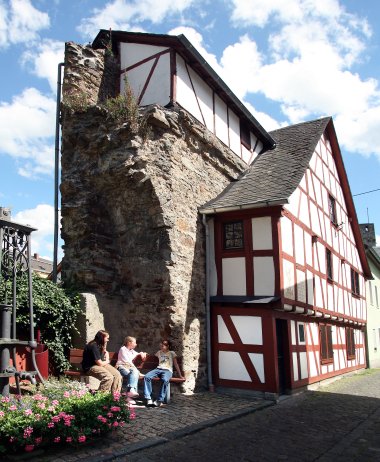 Stadtmauerhäuschen in der Hintermauergasse Lahnstein Kleines Fachwerkhaus mit rotem Dach, das direkt an einen massiven steinernen Rest der Stadtmauer angebaut ist. Das Gebäude steht an einer schmalen Straße.