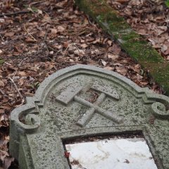 Grabstein auf dem Bergmannsfriedhof Lahnstein Friedrichssegen Detailaufnahme eines Grabsteins mit Schlägel und Eisen sowie verwitterten Inschriften.