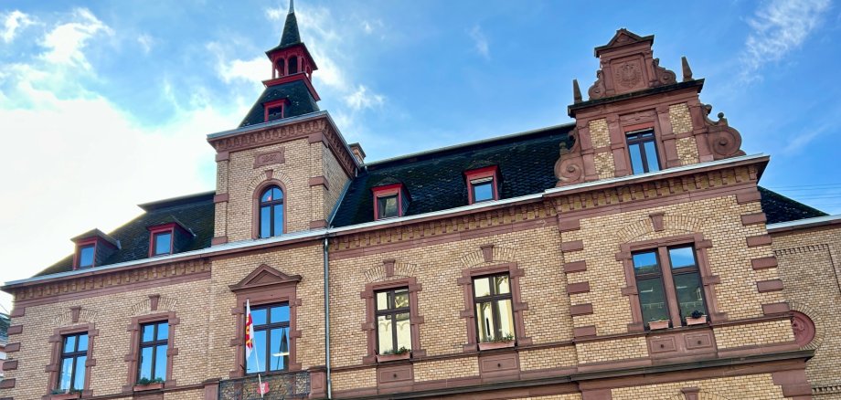Rathaus Lahnstein Historisches Stadthaus in Lahnstein mit repräsentativer Fassade aus gelbem Backstein und rötlichem Sandstein. Über dem Haupteingang steht der Schriftzug „Stadthaus“. Das Gebäude besitzt Rundbogenfenster, verzierte Giebel und einen markanten Turm mit spitzem Dach.